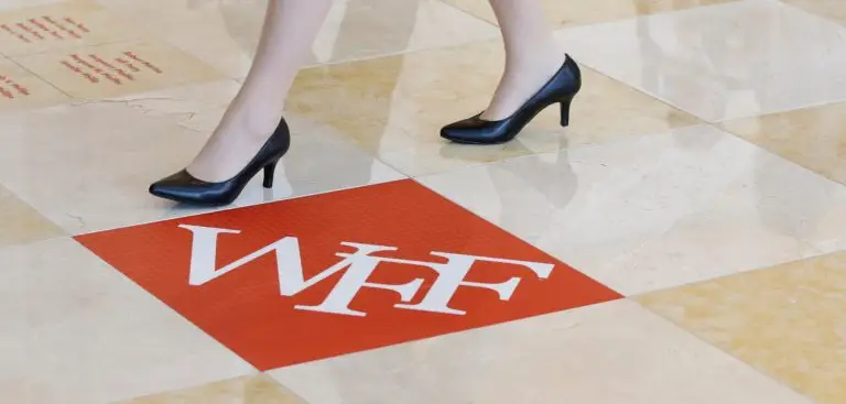 Black high-heeled shoes walking past a red WFF floor graphic.