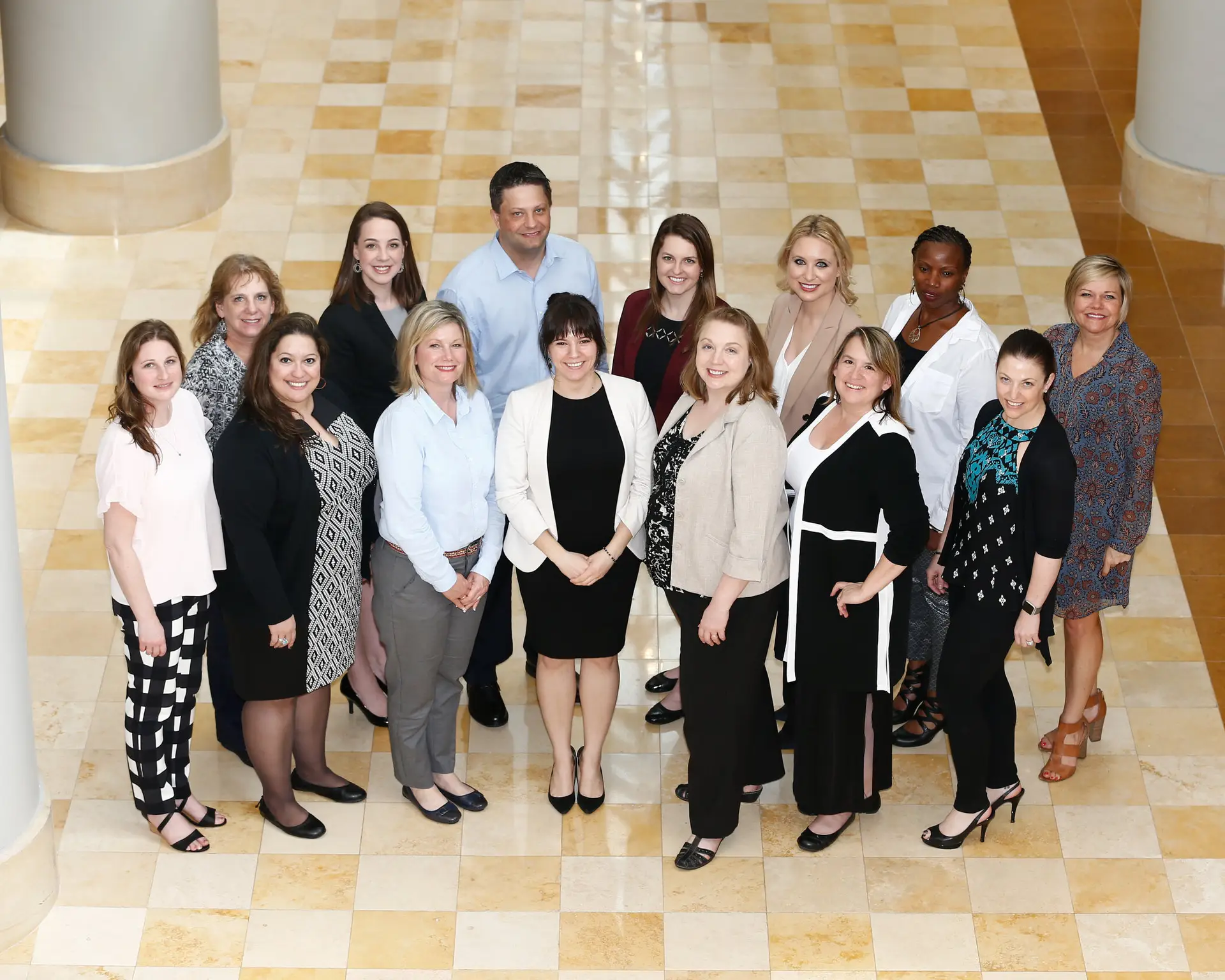 Group of people looking up toward the camera while standing on a tiled lobby floor.