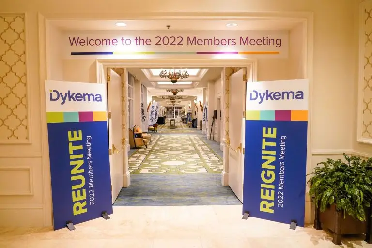 Dykema banners flanking a hallway entrance beneath a Welcome to the 2022 Members Meeting sign.