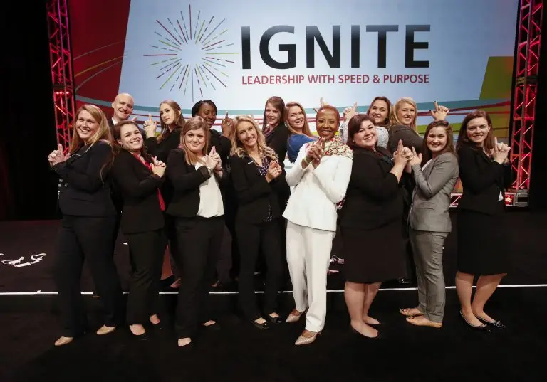 Group posing together with playful gestures beneath an Ignite Leadership with Speed and Purpose sign.
