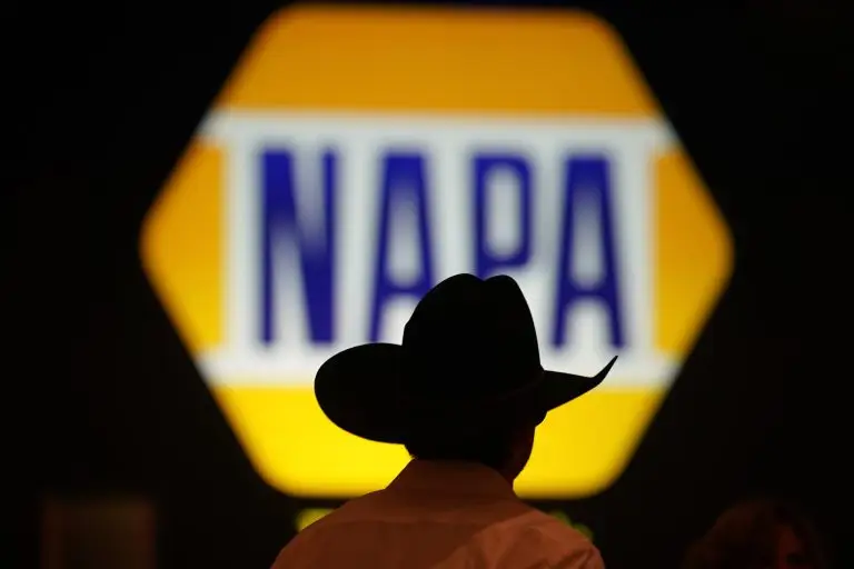 Silhouette of a person in a cowboy hat in front of an illuminated NAPA logo.