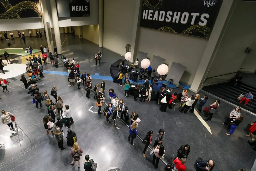Overhead view of attendees queued beside several portrait stations beneath a large Headshots sign.