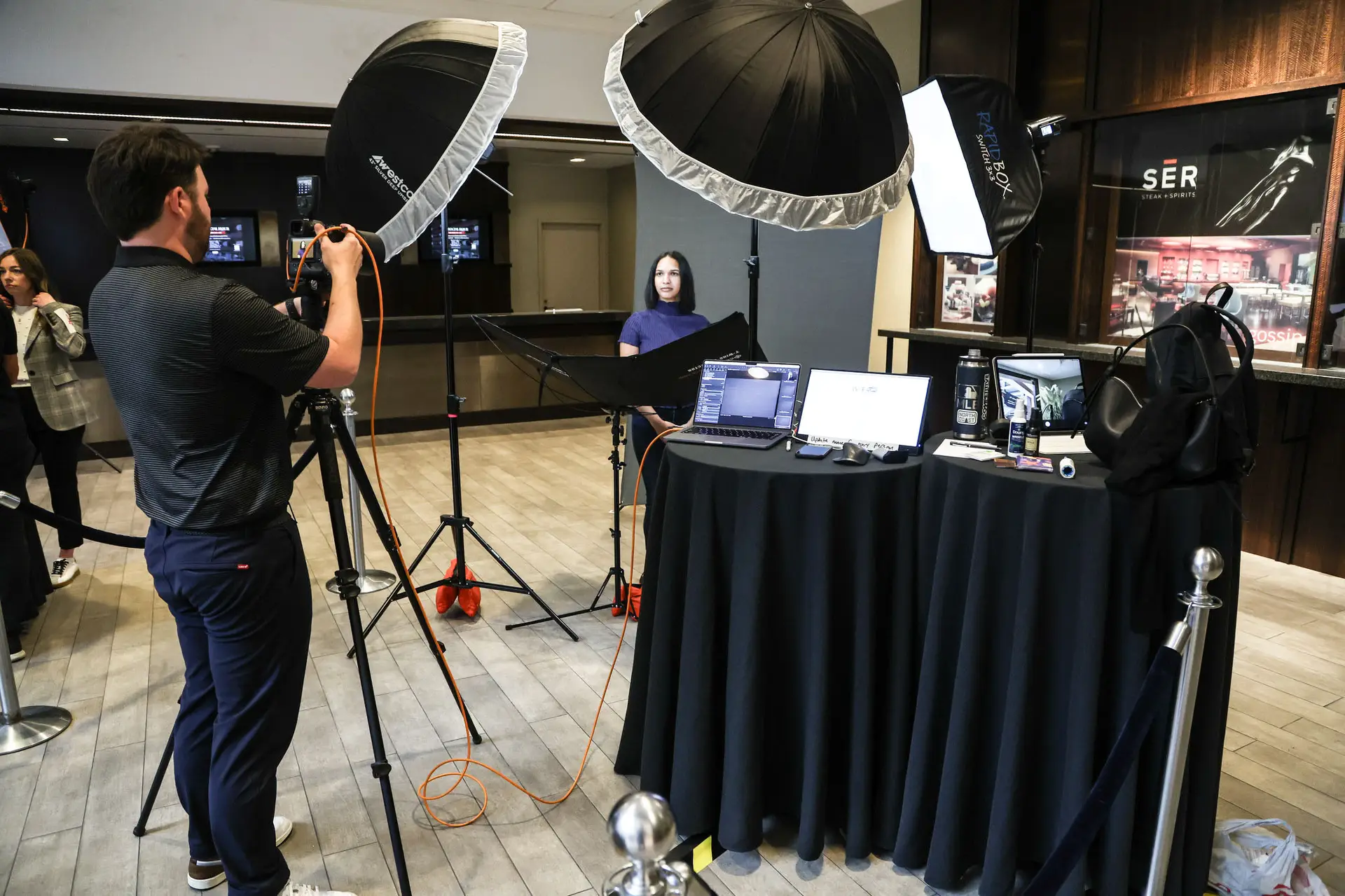 Photographer photographing an attendee at a headshot station in a hotel hallway near a restaurant entrance
